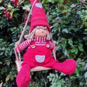 Red fabric Nordic boy with knitted hat on wooden swing